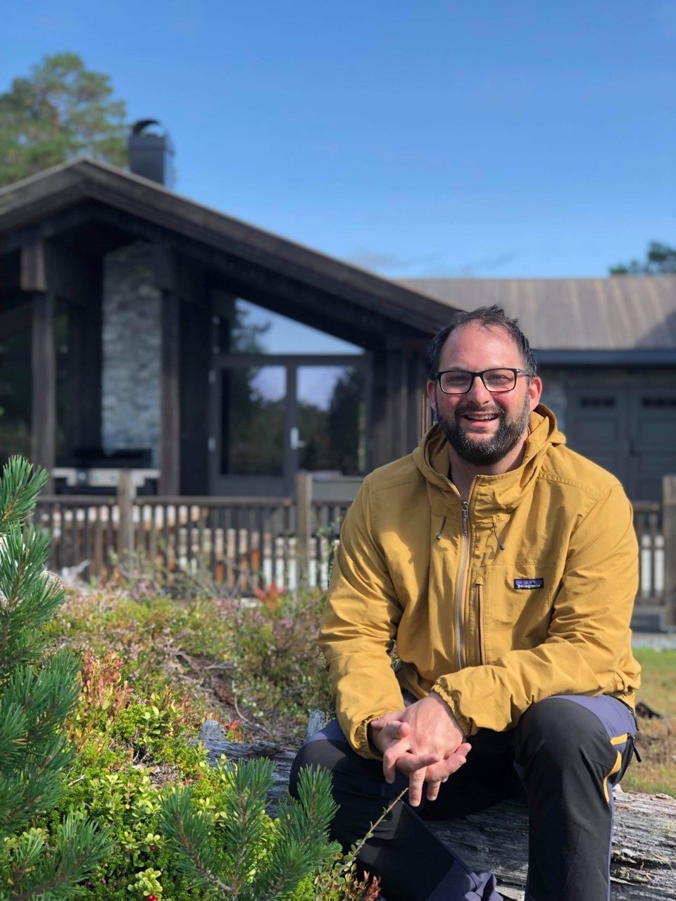 Natural environment, Glasses, Plant, Smile, Sky, Outerwear, Leaf, Building, Botany, Beard
