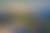 Panoramic sunset over a vast mountain range with rocky peaks in the foreground and a sun-drenched valley.