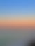 A tranquil ocean scene at sunset with a long pier, vibrant orange-blue sky, and white sandy beach.