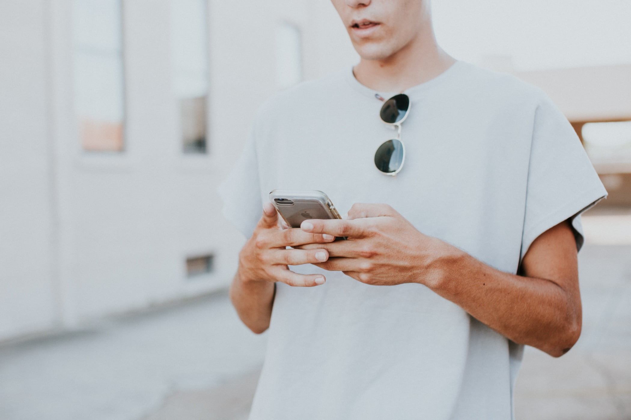 guy wearing all white with sunglasses while on his phone