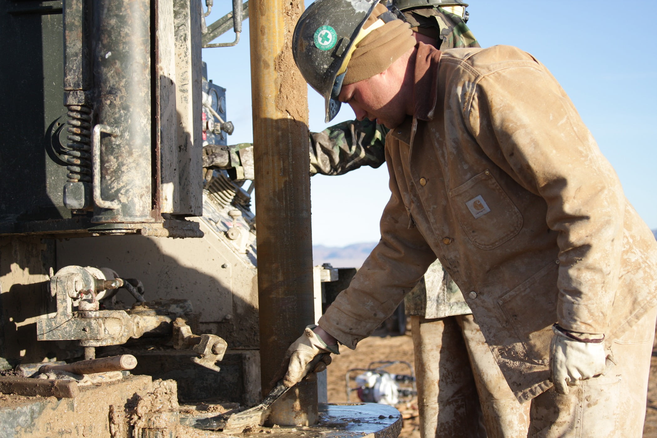 Petty Officer 1st Class Justin Richards, an equipment operator with the Naval Mobile Construction Battalion 40 drilling team, does a little mud cleaning during a geothermal project at a U.S. Marines facility in this 2008 photo. Source: Public Domain