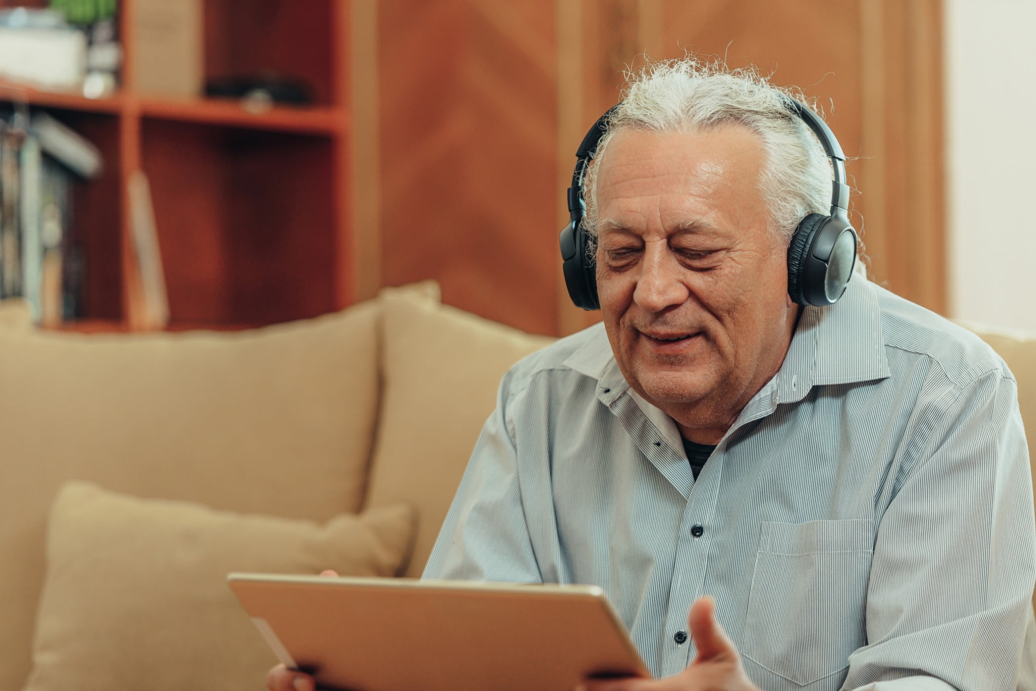 Older man on a tablet with headphones on