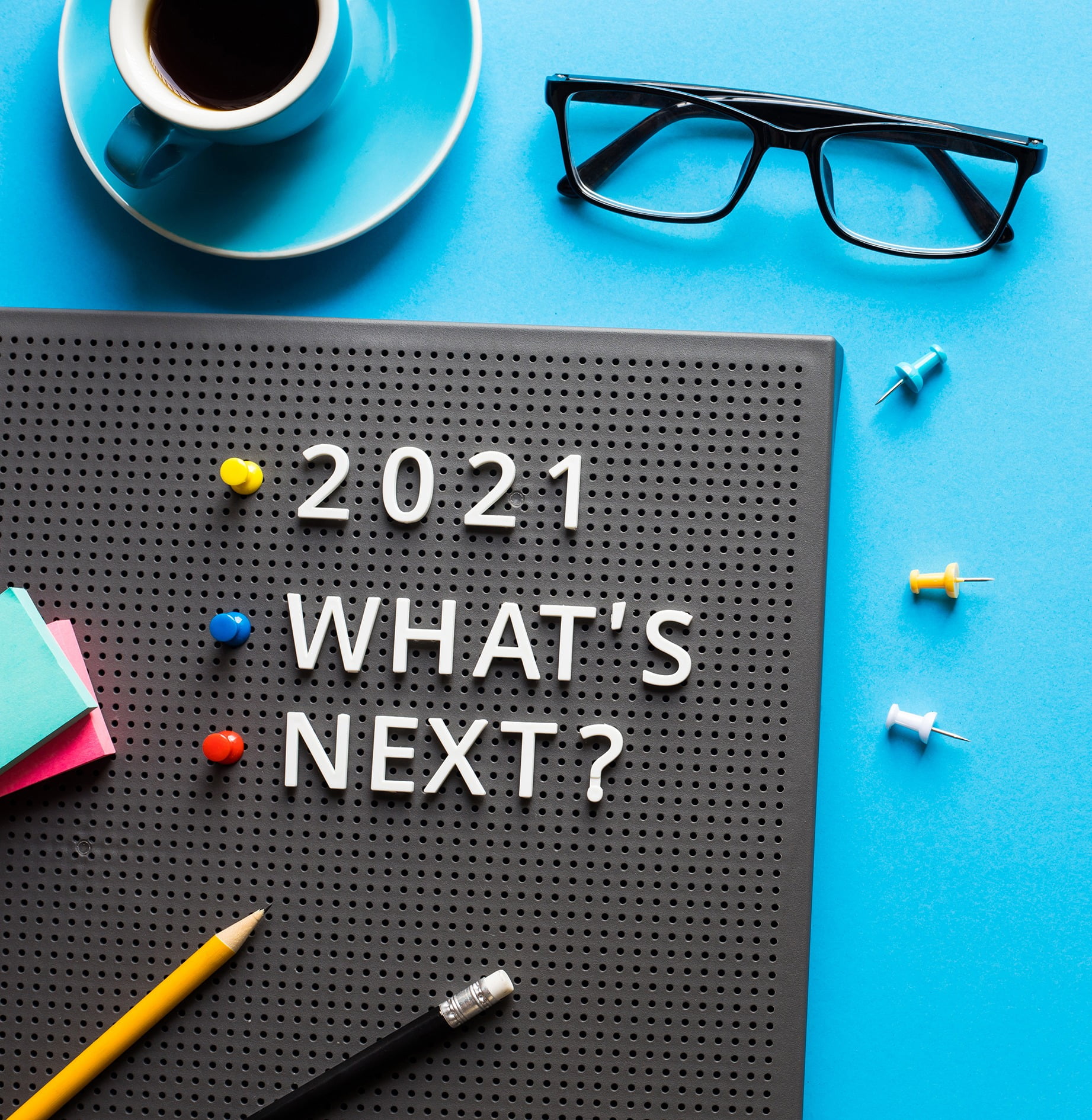 Business corkboard with 2021 What&#x27;s Next on desk with coffee, glasses and pencils