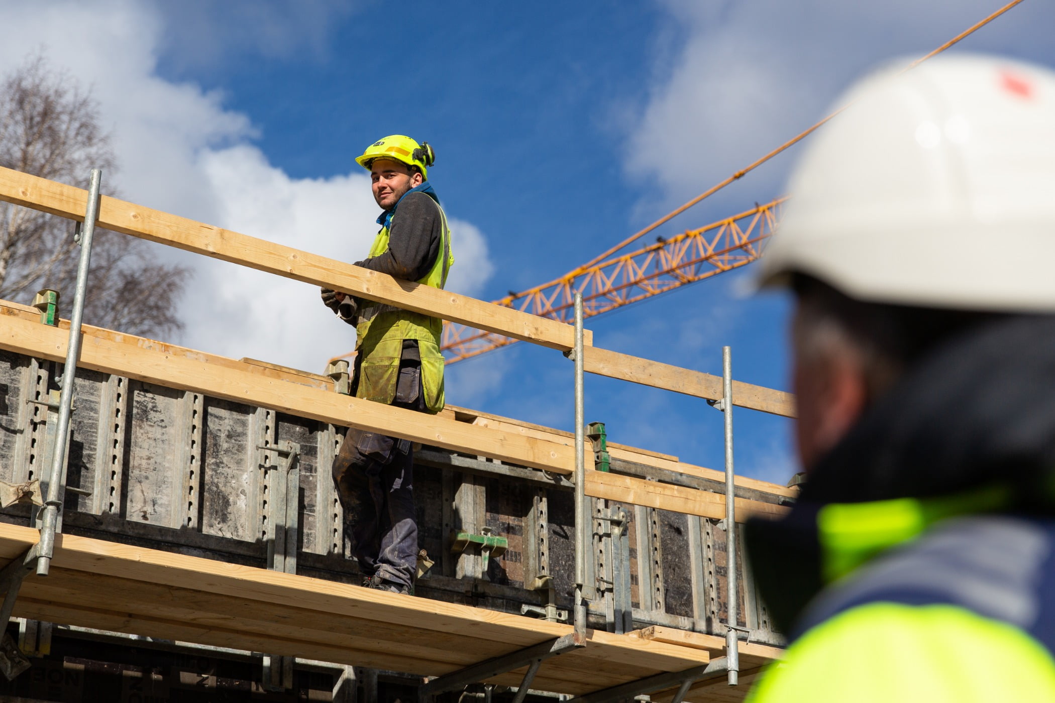 Hard hat, High-visibility clothing, Construction worker, Sky, Helmet, Outerwear, Cloud, Workwear, Tradesman, Engineer